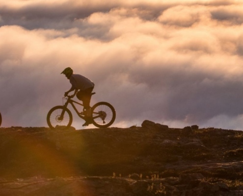 mountain bikes on mountain above clouds at sunrise