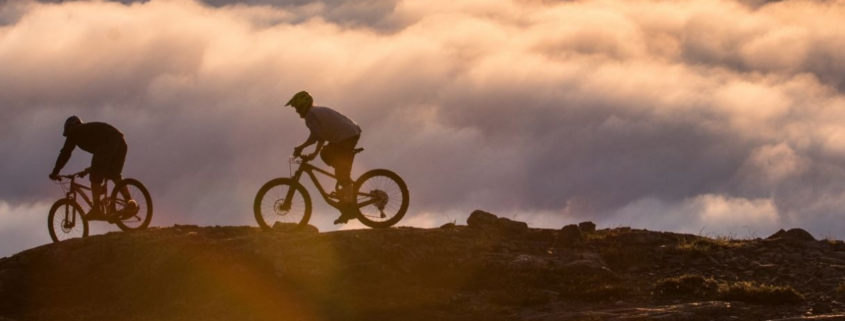 mountain bikes on mountain above clouds at sunrise