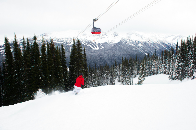 Peak to Peak Gondola Whistler going over a skiier in a red jacket